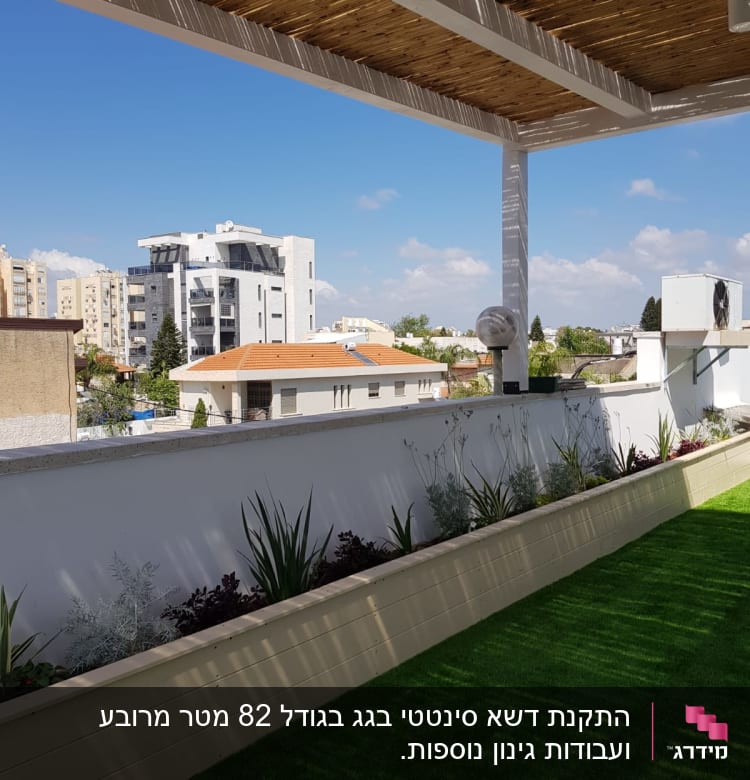 צמחים ירוקים בערוגה על מרפסת עם דשא סינתטי